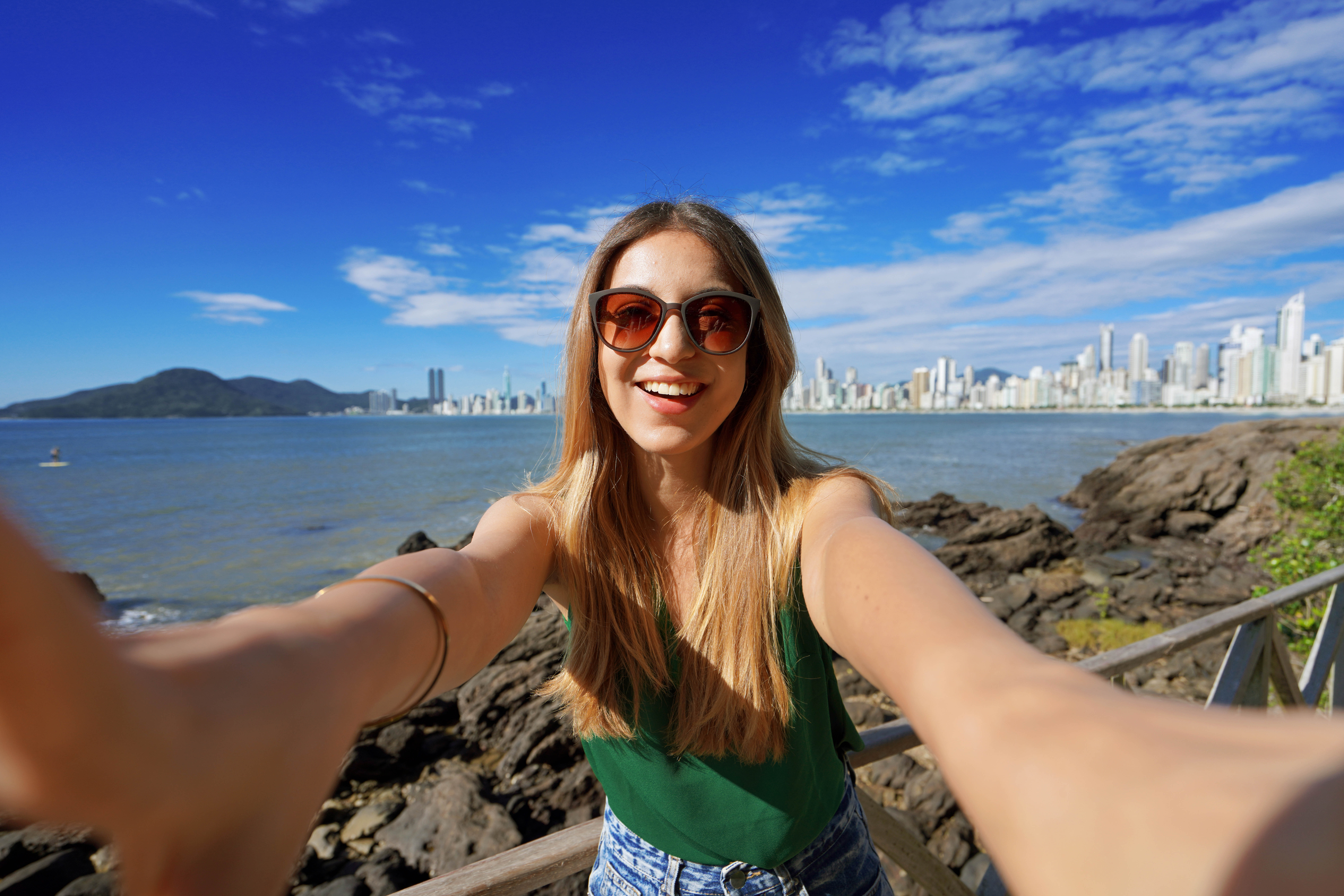 Trendy millennial girl having fun takes self portrait on summer vacation in Balneario Camboriu, Brazil