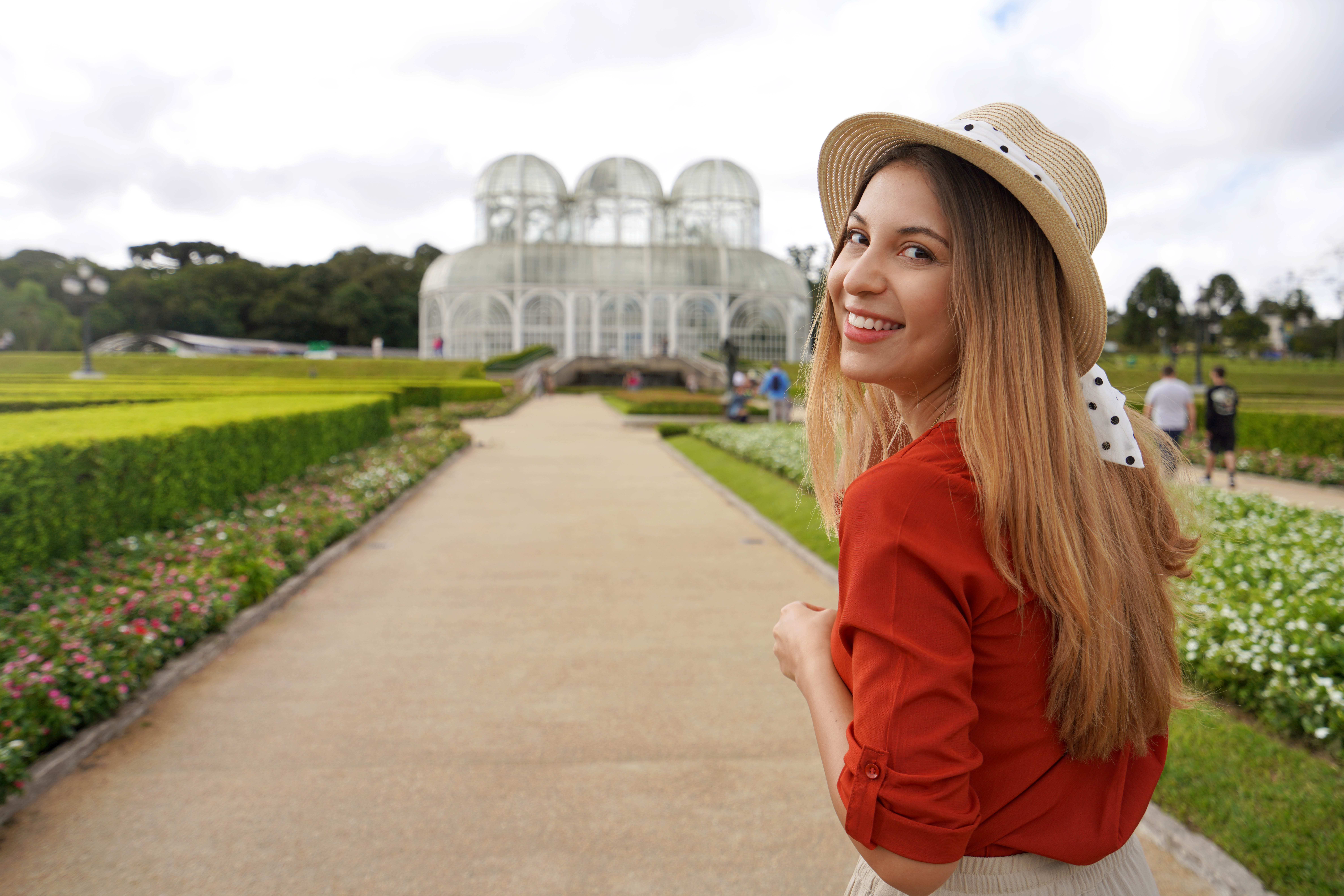 Portrait of happy smiling woman with hat walking in the Botanical Garden of Curitiba turns to the camera, Curitiba, Parana, Brazil