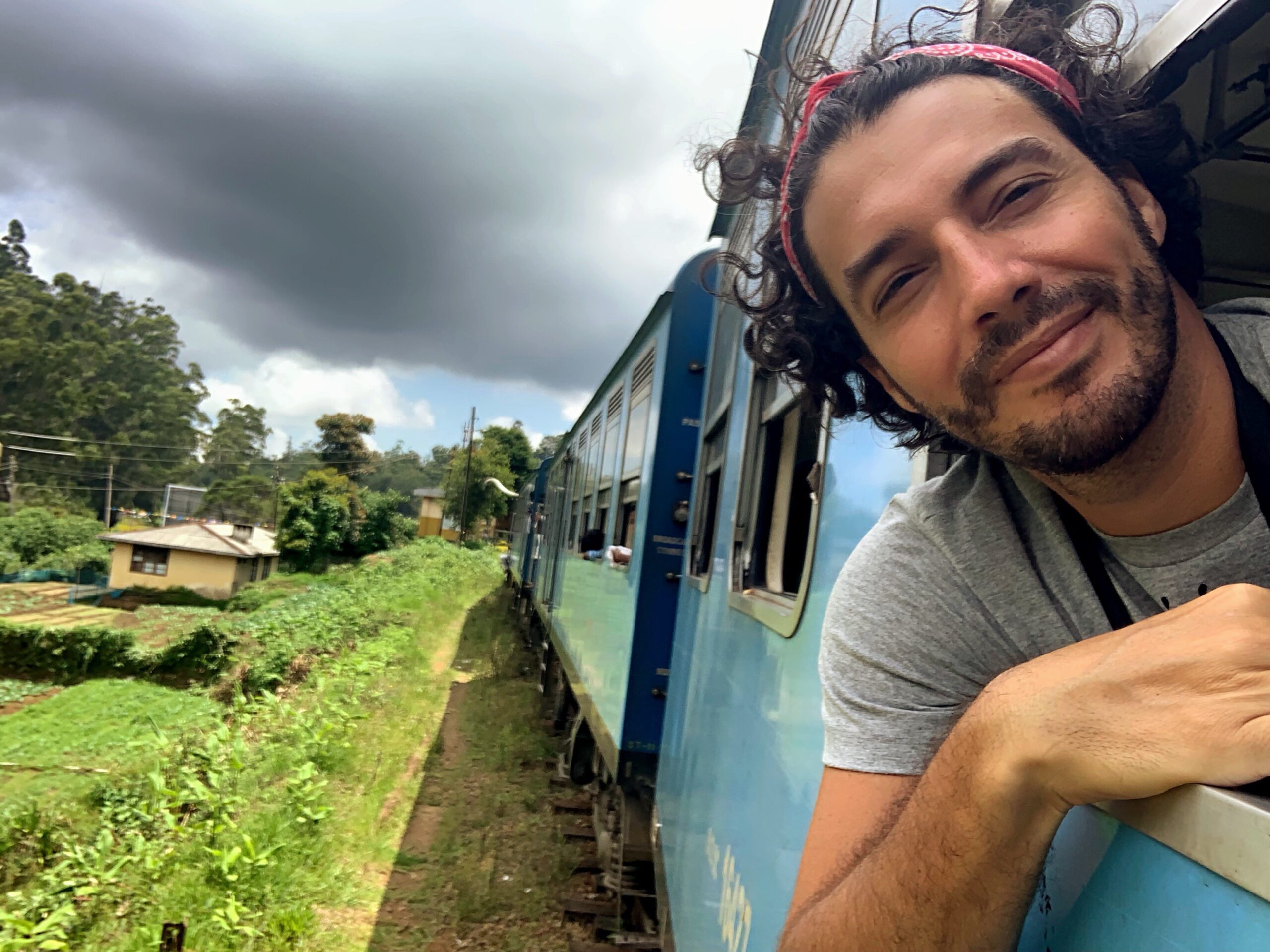 portrait-smiling-man-train-against-cloudy-sky