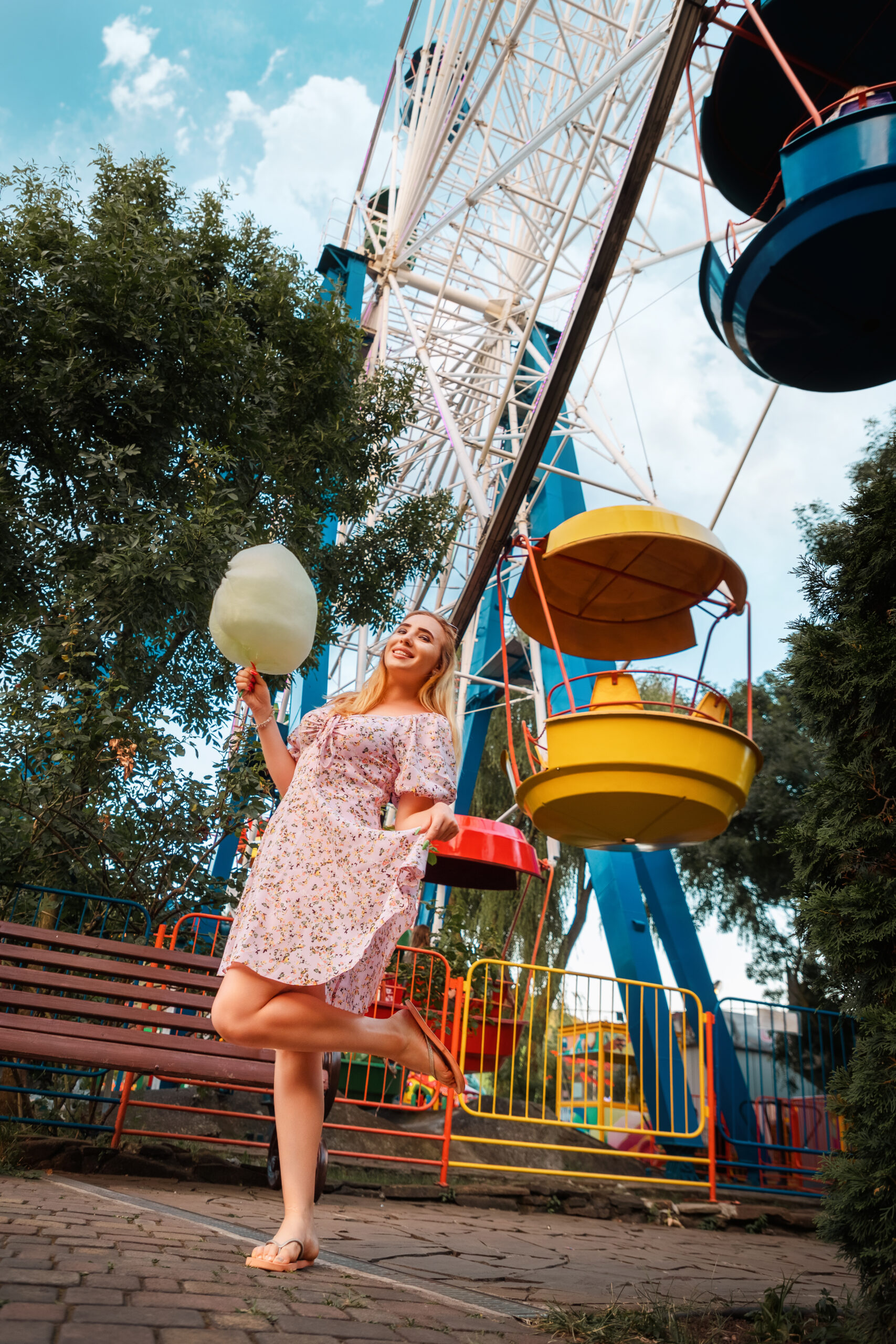 Summer festival. Dreamy pretty woman eating a cotton candy at amusement park. Vertical. The concept of vacation, holiday and happiness.